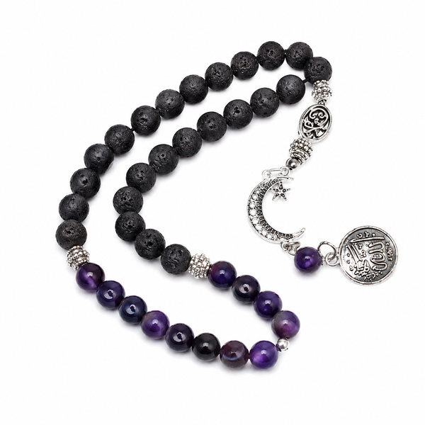 A beaded rosary featuring black lava stone beads and purple amethyst beads, accented with silver-toned metal charms including a crescent moon, star, and circular medallion.