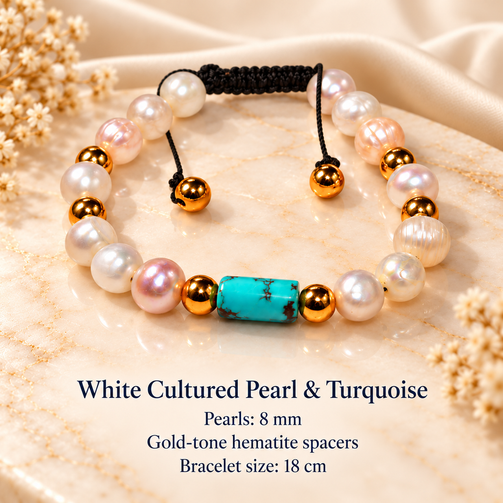 A beaded bracelet displayed on a beige marble slab with dried flowers. The bracelet features white cultured pearls, a turquoise-colored heart-shaped bead, gold-tone spacer beads, and a black adjustable cord.