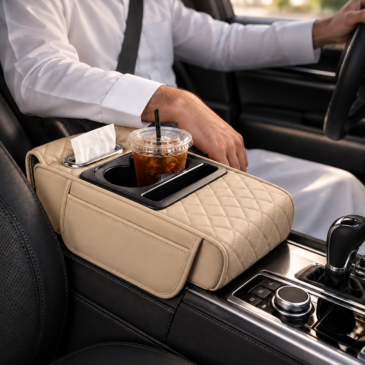 A beige quilted car center console organizer with cup holders, a tissue dispenser, and a drink holder, shown installed in a car with a driver visible.