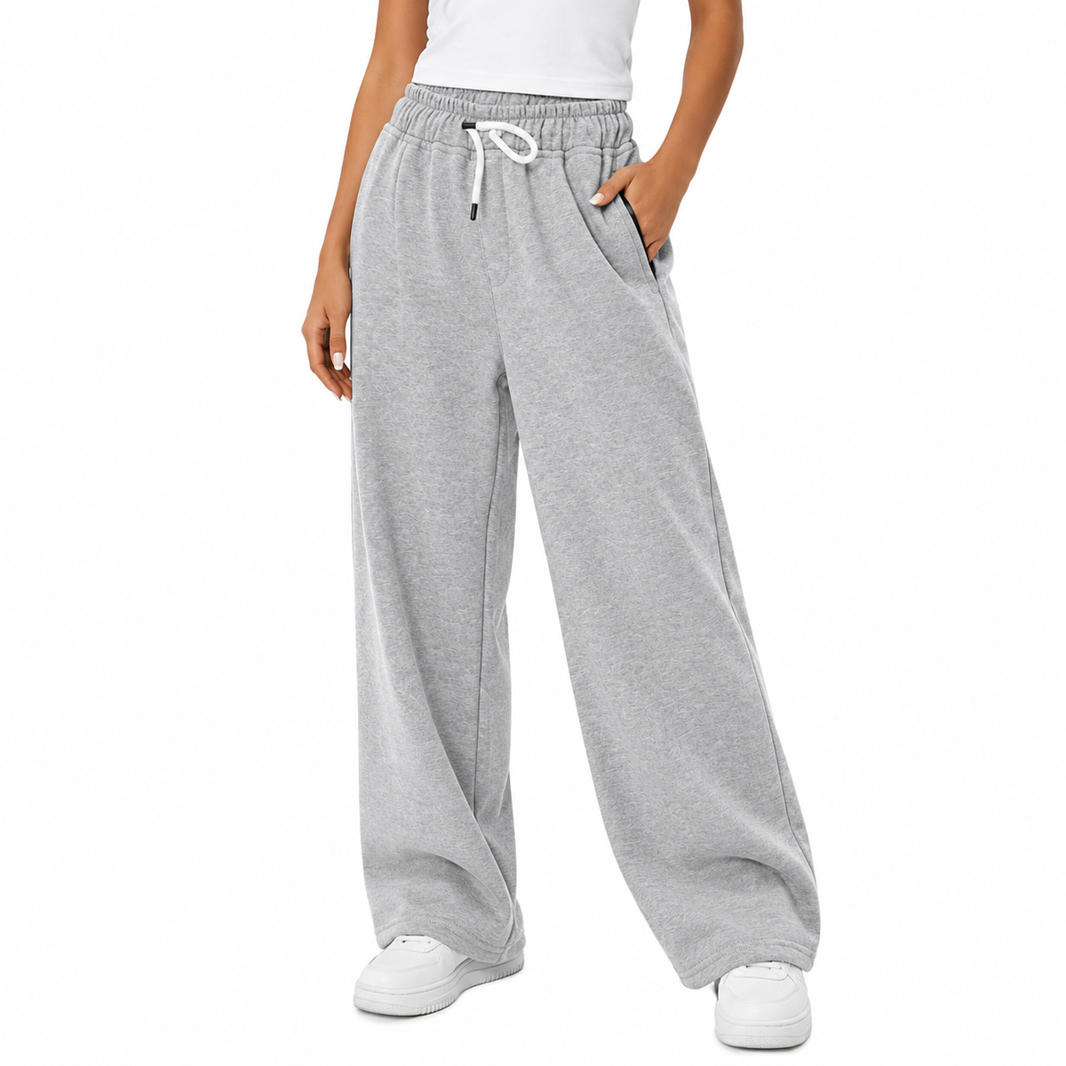 A person wearing light heather gray wide-leg sweatpants with an elastic waistband, white drawstring, and side pockets, paired with a white top and white sneakers on a plain white studio background.7AGAT Shopping grey melton wide leg sweatpants with relaxed fit
