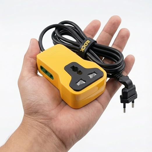 A yellow and black UK three-pin wall plug adapter with a coiled black power cord, held in a person's hand against a plain white background.