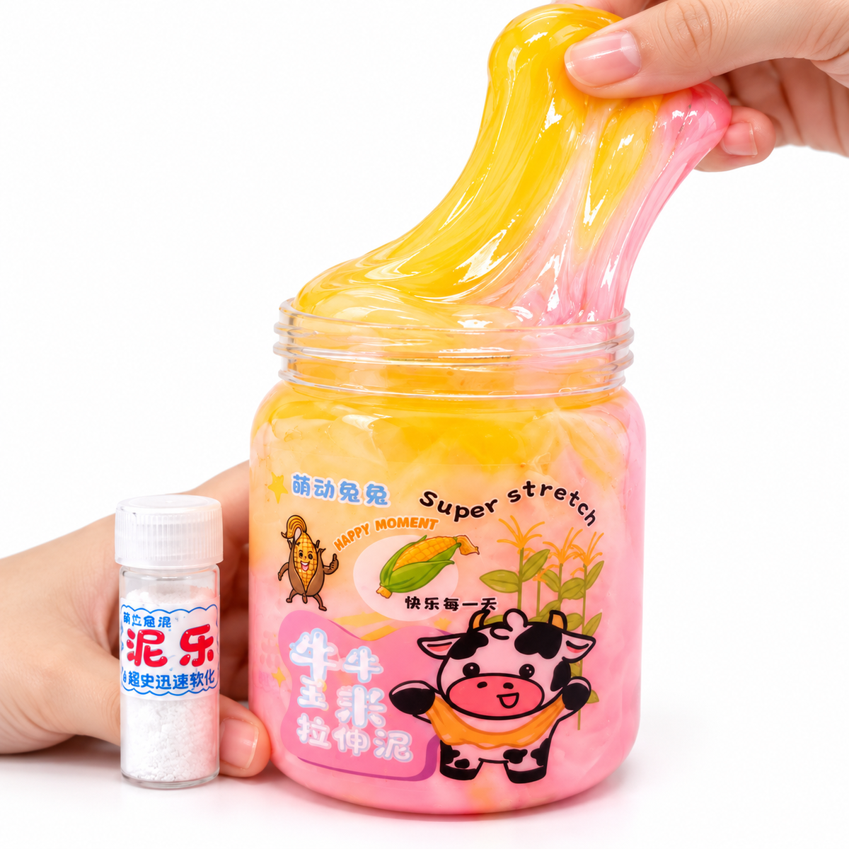 A hand stretches a translucent yellow and pink slime inside a clear jar with cartoon graphics, while another hand holds a small bottle of white powder next to it on a white background.