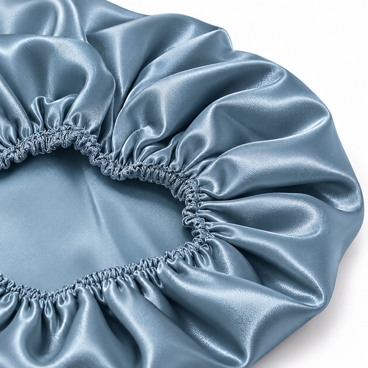 A close-up of a light blue satin sleep cap or bonnet with gathered elastic edges, shown on a white background.