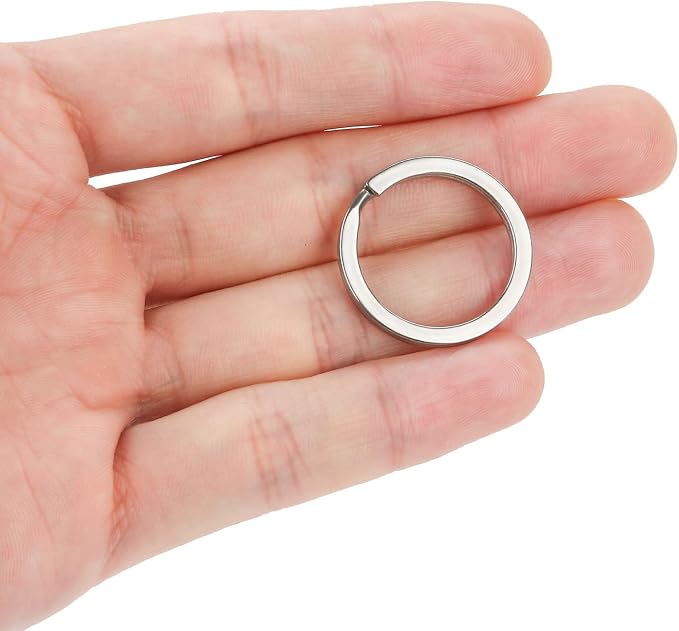 A polished silver metal split ring keychain held in the palm of a hand against a plain white background.