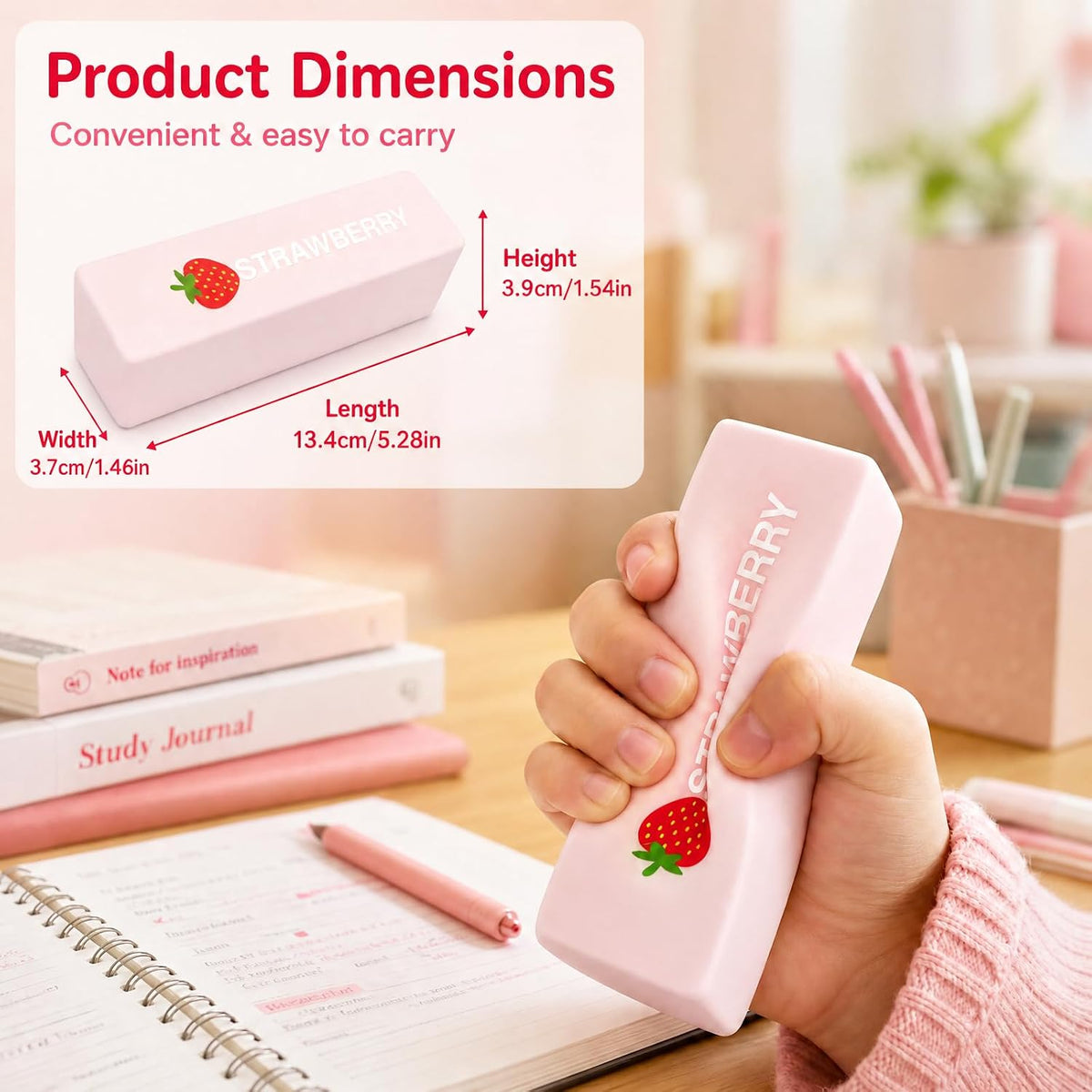 A hand holds a pink strawberry-shaped eraser in a desk setting, with a product dimension diagram overlay showing the eraser's width, length, and height.