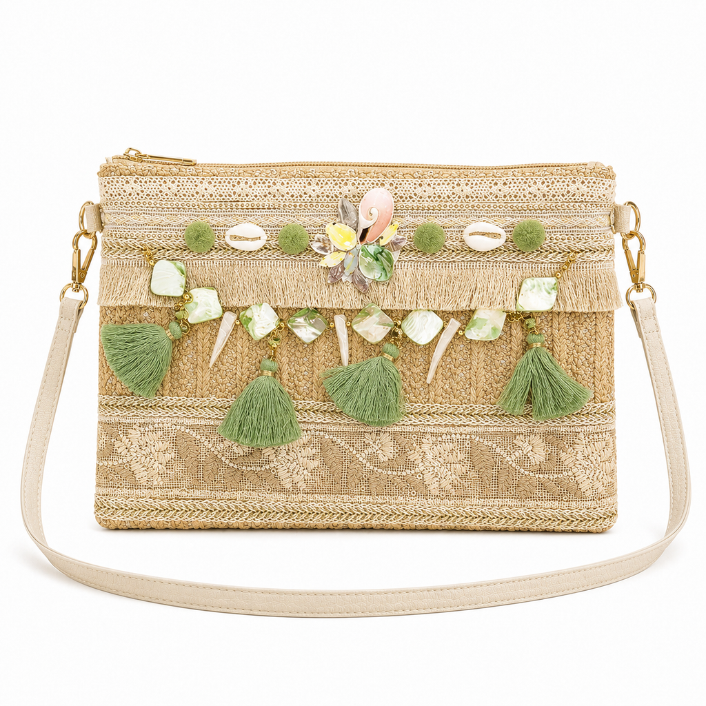 A woven straw clutch bag with a gold zipper, decorated with green tassels, cowrie shells, and a central floral embellishment, shown on a white background.