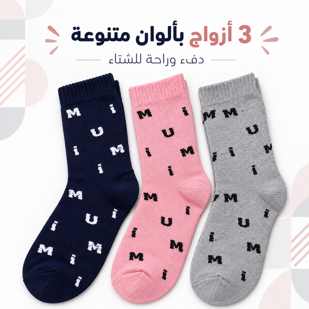 Three pairs of baby socks with a repeating 'MUM' pattern, shown in navy blue, pink, and heather gray on a light background with Arabic promotional text at the top.