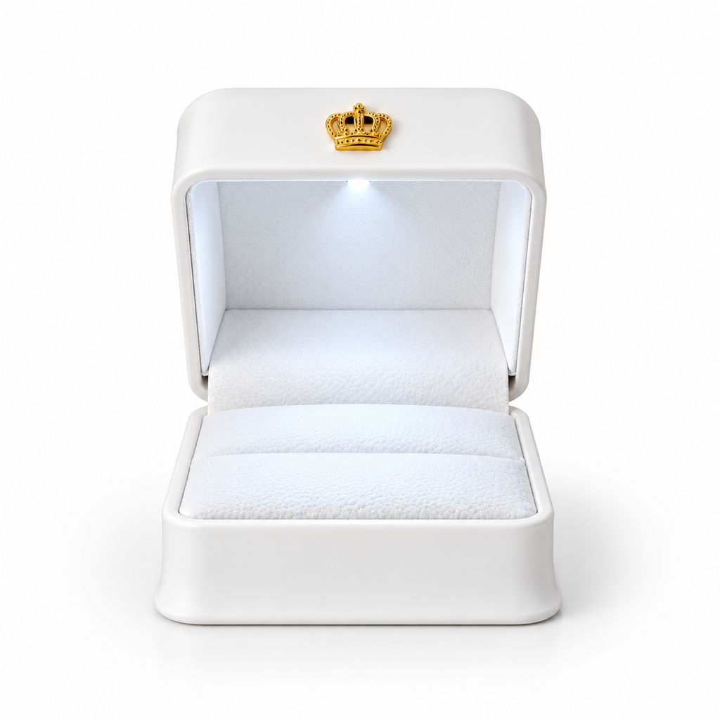 A white ring box with an open lid, featuring a small gold crown emblem on the front. The interior is lined with white velvet and includes an integrated light that illuminates the ring cushion, set against a clean white background.