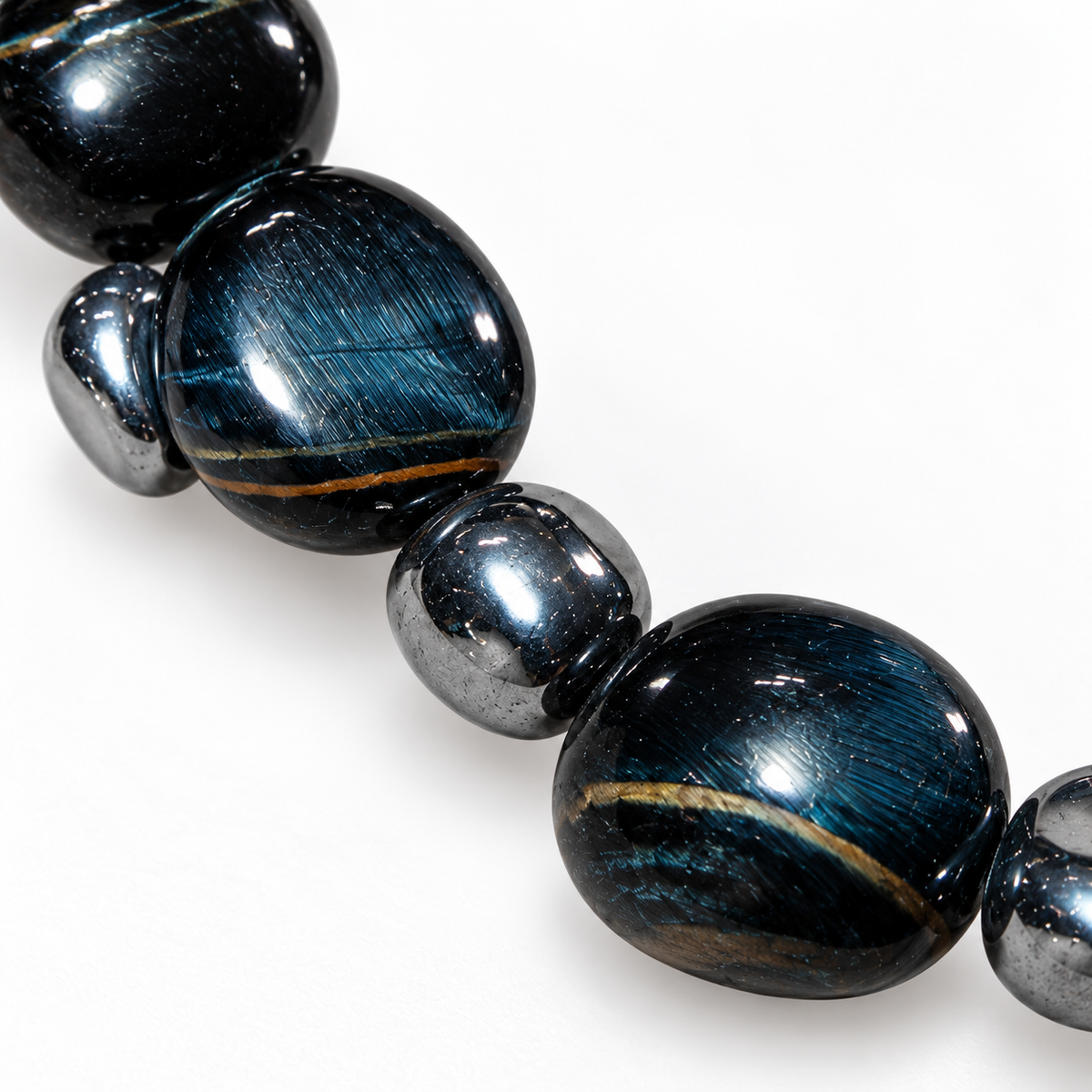 7agat close-up of polished dark Hawk's Eye gemstone beads and reflective silver-tone hematite spacers