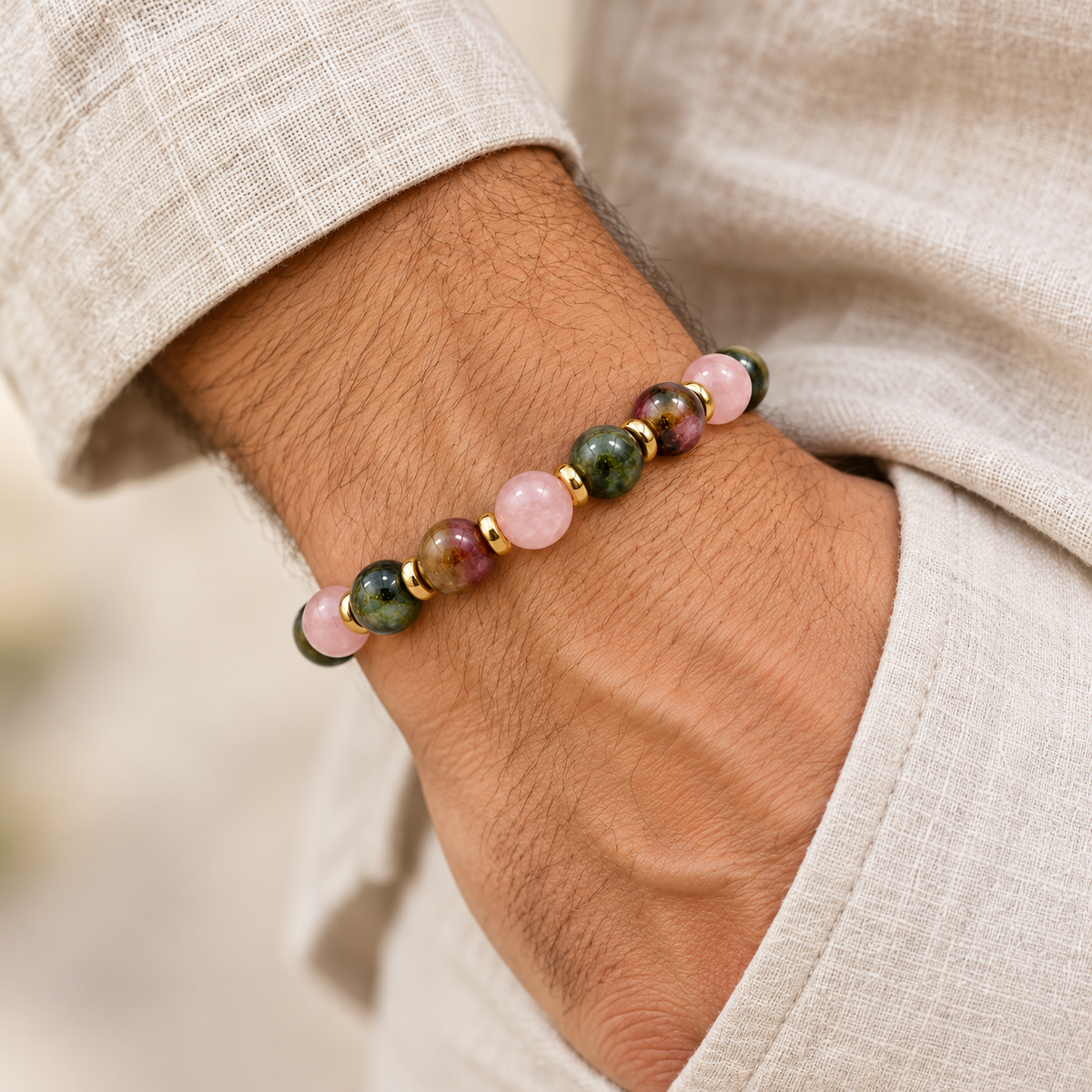 7agat Tourmaline and Rose Quartz bracelet with gold Hematite accents styled on a man's wrist.