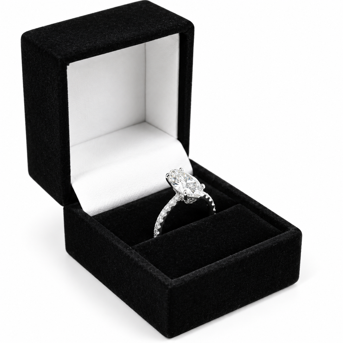 A silver-toned diamond engagement ring with a large oval center stone and pavé band, displayed inside an open black velvet ring box with a white interior on a white background.